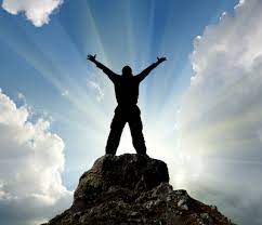 A man standing on top of a mountain with arms in the air.